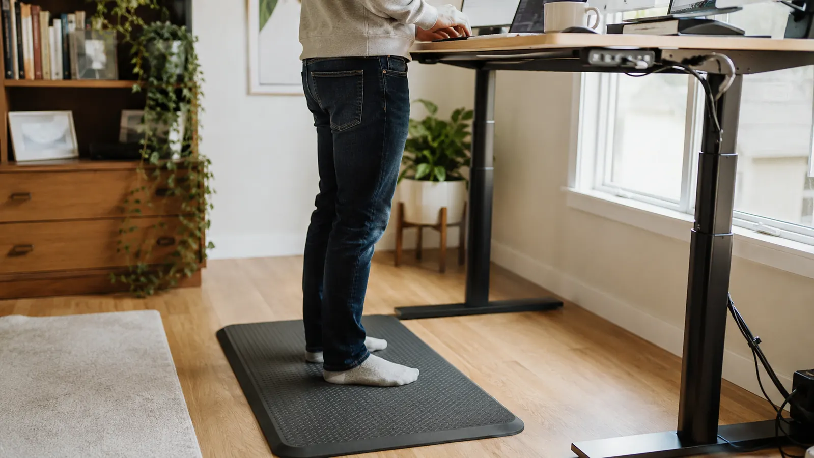 Ergodriven Topo anti-fatigue standing mat beside a standing desk showing the contoured surface with raised dome and slopes