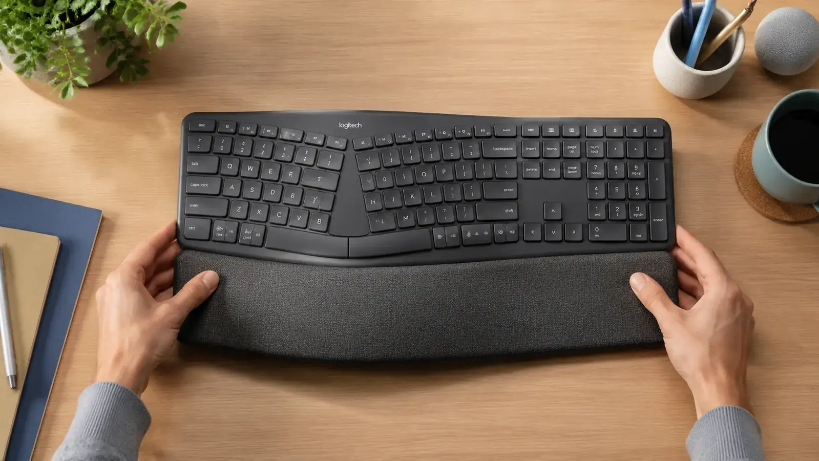 Hands resting on a split ergonomic keyboard showing neutral wrist angle, viewed from the side