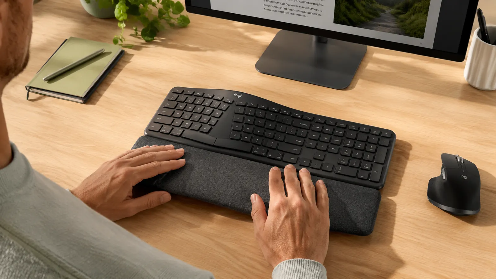 Close-up of hands typing incorrectly on an ergonomic keyboard with wrists pressed down on the palm rest during keystrokes