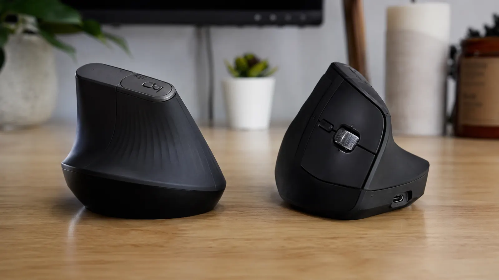 Logitech MX Vertical mouse on a clean wooden home office desk next to a keyboard and notebook